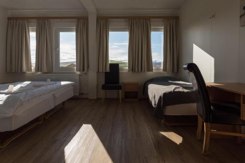 a bedroom with two beds and a desk and windows at Guesthouse Brekka in Brekka