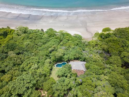 an aerial view of a beach with trees and the ocean at Morgan's Rock in San Juan del Sur