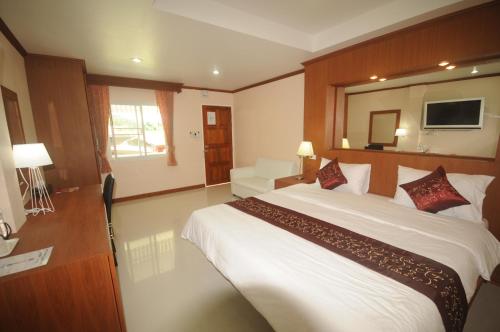 a bedroom with a large white bed and a television at Chinathip Yusabuy in Nan