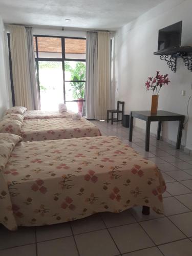 1 dormitorio con 2 camas, mesa y ventana en Balcon Gueela, en Santa Cruz Huatulco