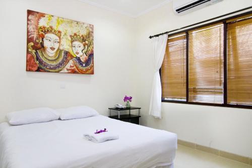 Un dormitorio con una cama blanca y un cuadro en la pared. en Bali Paradise Apartments, en Sanur