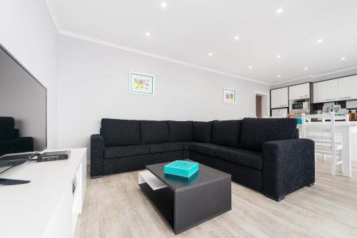 a living room with a black couch and a table at Ilhéu do Areeiro in Madalena