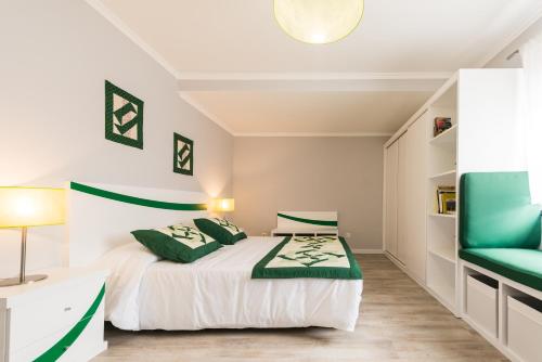 a bedroom with a bed and a green chair at Ilhéu do Areeiro in Madalena
