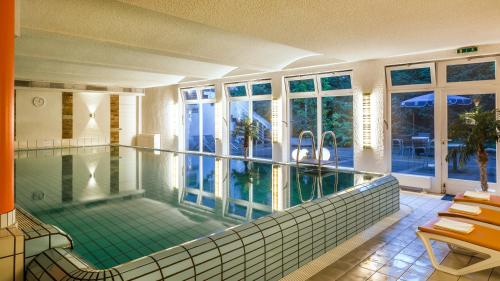 a large swimming pool in a house with a pool at Parkhotel Nümbrecht in Nümbrecht