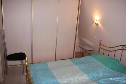 ein kleines Schlafzimmer mit einem Bett und einem Stuhl in der Unterkunft Butas Prie Nemuno in Druskininkai