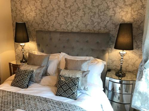 a bedroom with a bed with pillows and two lamps at Millwalk Apartment in Witney