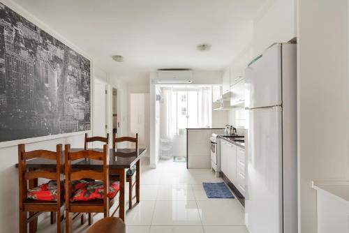 a kitchen with a table and chairs and a refrigerator at Apto 2 quartos, 1 quadra do Mar/Shop. Atlantico in Balneário Camboriú