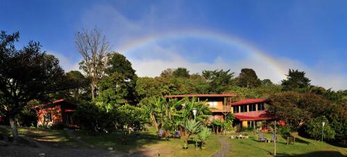 a rainbow in the sky over a house with trees at Arco Iris Lodge in Monteverde Costa Rica