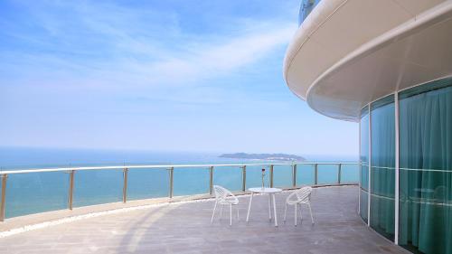a balcony with chairs and a table and the ocean at The Mangrovetree Sanya Resort in Sanya