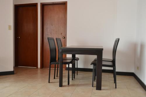 una mesa y sillas en una habitación con puerta en Apartahotel Doble3 en Paipa