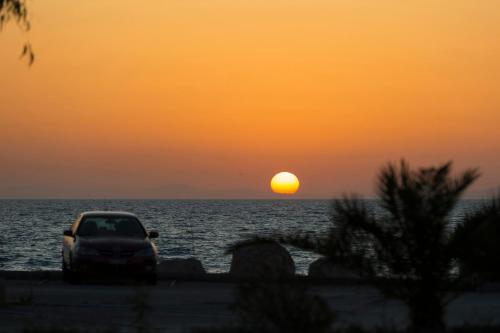a car parked on the beach at sunset at Delfini Hotel in Patra