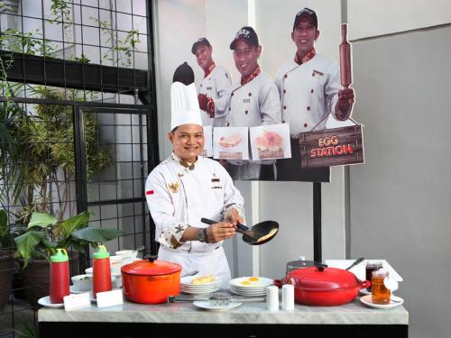 a chef standing in a kitchen holding a spoon at Swiss-Belinn Tunjungan Surabaya in Surabaya
