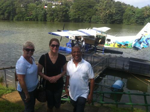 three people standing next to a boat on a lake at Witherspoon Lodge in Kandy