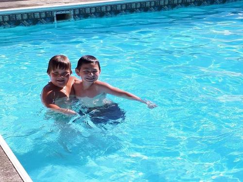 twee jonge jongens zwemmen in een zwembad bij Falcon Nest Motel in Duncan