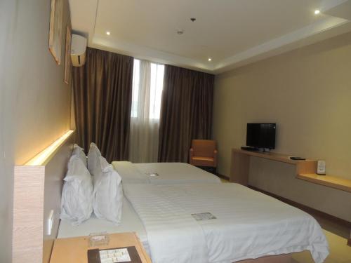 a hotel room with a white bed and a television at Dela Chambre Hotel in Manila