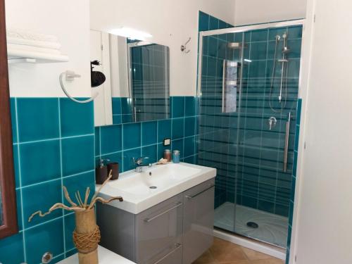 baño con lavabo y ducha con azulejos azules en Agave Scopello, en Scopello