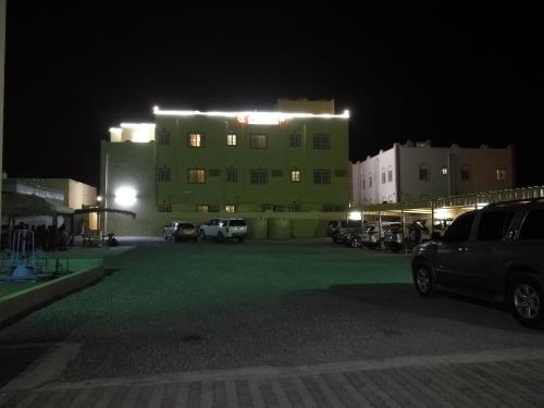 a green building with cars parked in front of it at night at Salassel Al Jabal Al Akhdar Guesthouse in Al ‘Aqar