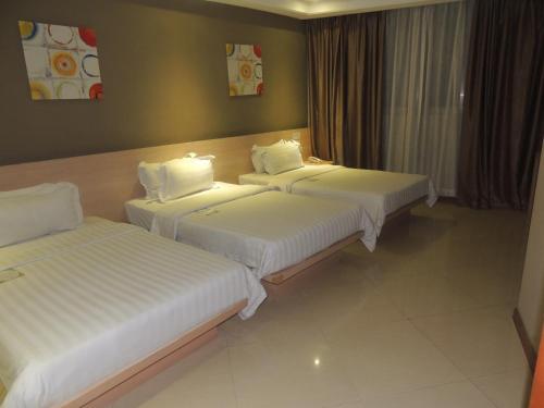 two beds in a hotel room with white sheets at Dela Chambre Hotel in Manila