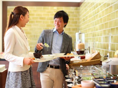 a man and a woman holding a plate of food at Hotel Forza Nagasaki in Nagasaki