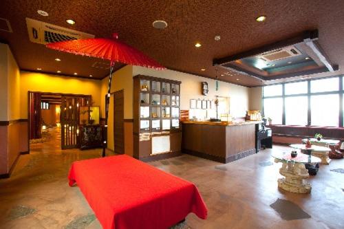 une chambre avec une table rouge et un parapluie rouge dans l'établissement Hamazen Ryokan, à Hinagu