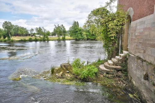 a river next to a brick building with water at Hôtel de France in Saint-Savin-sur-Gartempe