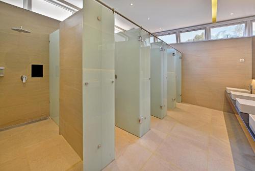 a bathroom with a row of stalls and a sink at Grand Whiz Hotel Trawas Mojokerto in Trawas