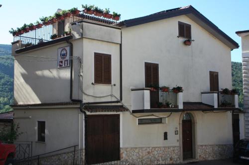 a white house with a balcony with plants on it at Bed e Breakfast Erica in Conflenti Inferiore