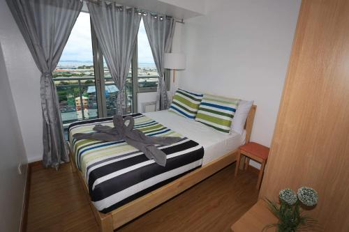 Schlafzimmer mit einem Bett und einem großen Fenster in der Unterkunft Maui Condotel Azure Residence in Manila