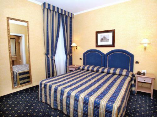 Habitación de hotel con cama azul y espejo en Hotel Valle, en Roma