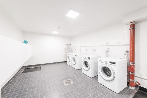 a laundry room with three washing machines and a tile floor at Forenom Serviced Apartments Helsinki Lauttasaari in Helsinki