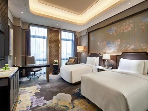 a hotel room with two beds and a desk at Wanda Vista Harbin in Harbin