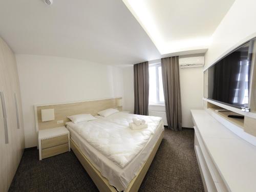um pequeno quarto com uma cama e uma televisão em Apartment OneClickRent 2 SmartHouse em Chisinau