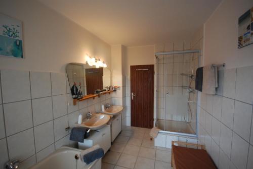a bathroom with two sinks and a tub and a shower at Gästehaus Spengler in Celle