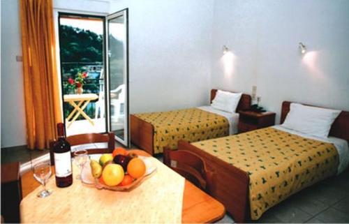 a hotel room with two beds and a bowl of fruit on a table at Ionion Hotel in Syvota