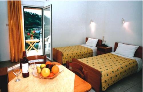 een hotelkamer met 2 bedden en een tafel met een fruitschaal bij Ionion Hotel in Sivota