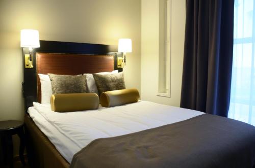 a bedroom with a large bed with two pillows at Home Hotel Bilan in Karlstad