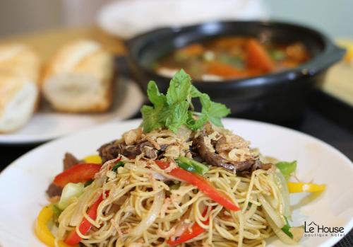 a white plate of food with noodles and vegetables at Le House Boutique Hotel - 100m to the beach in Da Nang