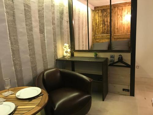 une salle à manger avec une table et un fauteuil en cuir dans l'établissement Le lingotin, à Honfleur