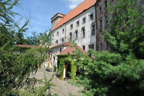 a large brick building with a red roof at Zamek Otmuchów in Otmuchów