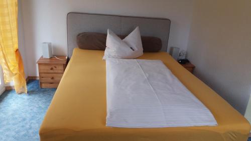 a large yellow bed with two pillows on it at Hotel Sonnenhof in Cham