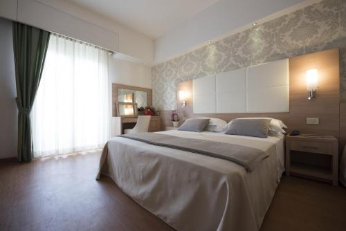 a bedroom with a large white bed and a window at Michelangelo Cesenatico in Cesenatico