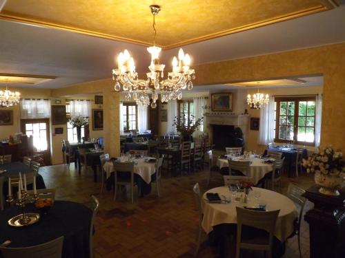 une salle à manger avec des tables et des chaises ainsi qu'un lustre dans l'établissement Château de Passières, à Chichilianne