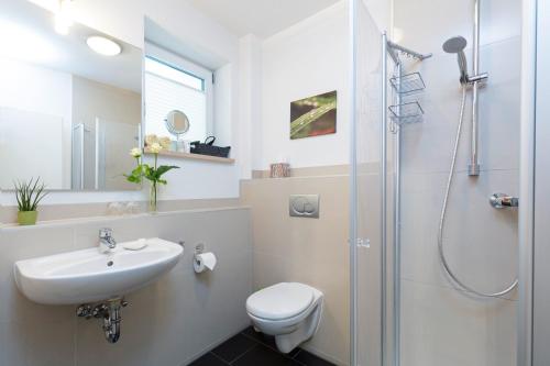 a bathroom with a sink toilet and a shower at Hotel Villa Rosa in Allershausen