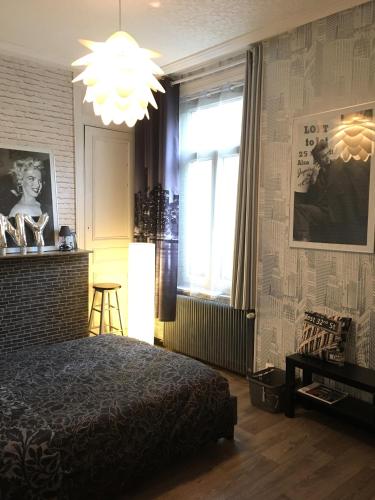 a bedroom with a bed and a window and a chandelier at La Maison Du Bulot in Fruges