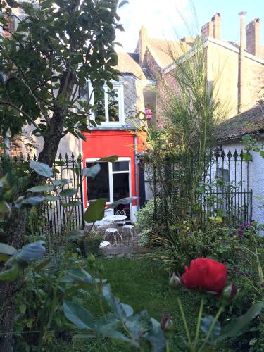 a garden with a red house and a red rose at La Maison Du Bulot in Fruges