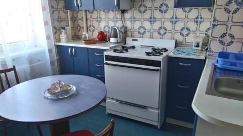 eine Küche mit einem weißen Herd und einem Tisch in der Unterkunft Apartment Kalku 2 in Riga