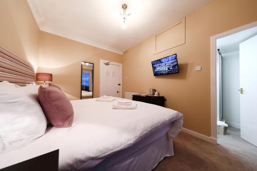 a bedroom with a large bed with a tv on the wall at The Station Hotel in Carnoustie