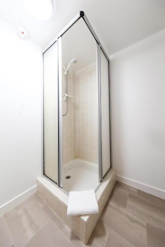 a glass shower in a white bathroom with a towel at The Station Hotel in Carnoustie