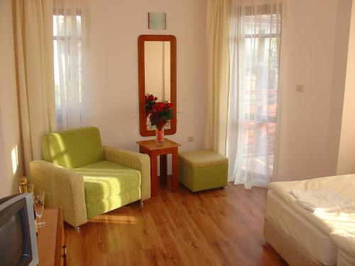 a living room with a green chair and a mirror at Family Hotel Saint Nikola and Free parking in Nesebar