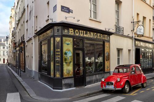 a small red car parked in front of a building at Hotel du Petit Moulin in Paris